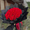 Red roses bouquet in dramatic all-black wrap with pink ribbon